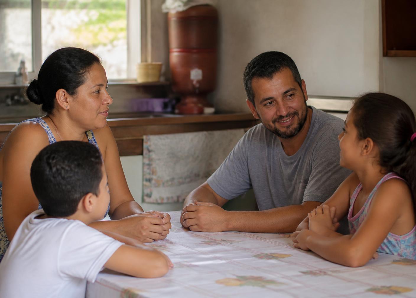 Família brasileira conversando à mesa em casa
